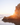 Sunset over a rocky outcrop with ocean waves reflecting on wet sand, capturing the tranquil beauty of the coast.