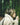 Woman in cream sherpa jacket gently smelling moss-covered tree in a serene forest setting