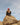 Man sitting on a rocky peak under a blue sky, evoking solitude and reflection
