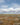 Vast grassland with golden shrubs, distant hills, and a partly cloudy sky in a semi-arid landscape