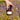 Hand holding a jar of candle in front of a field of flowers
